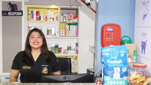 Una recepcionista sonríe en el mostrador, delante de estantes con medicinas, alimento balanceado y accesorios